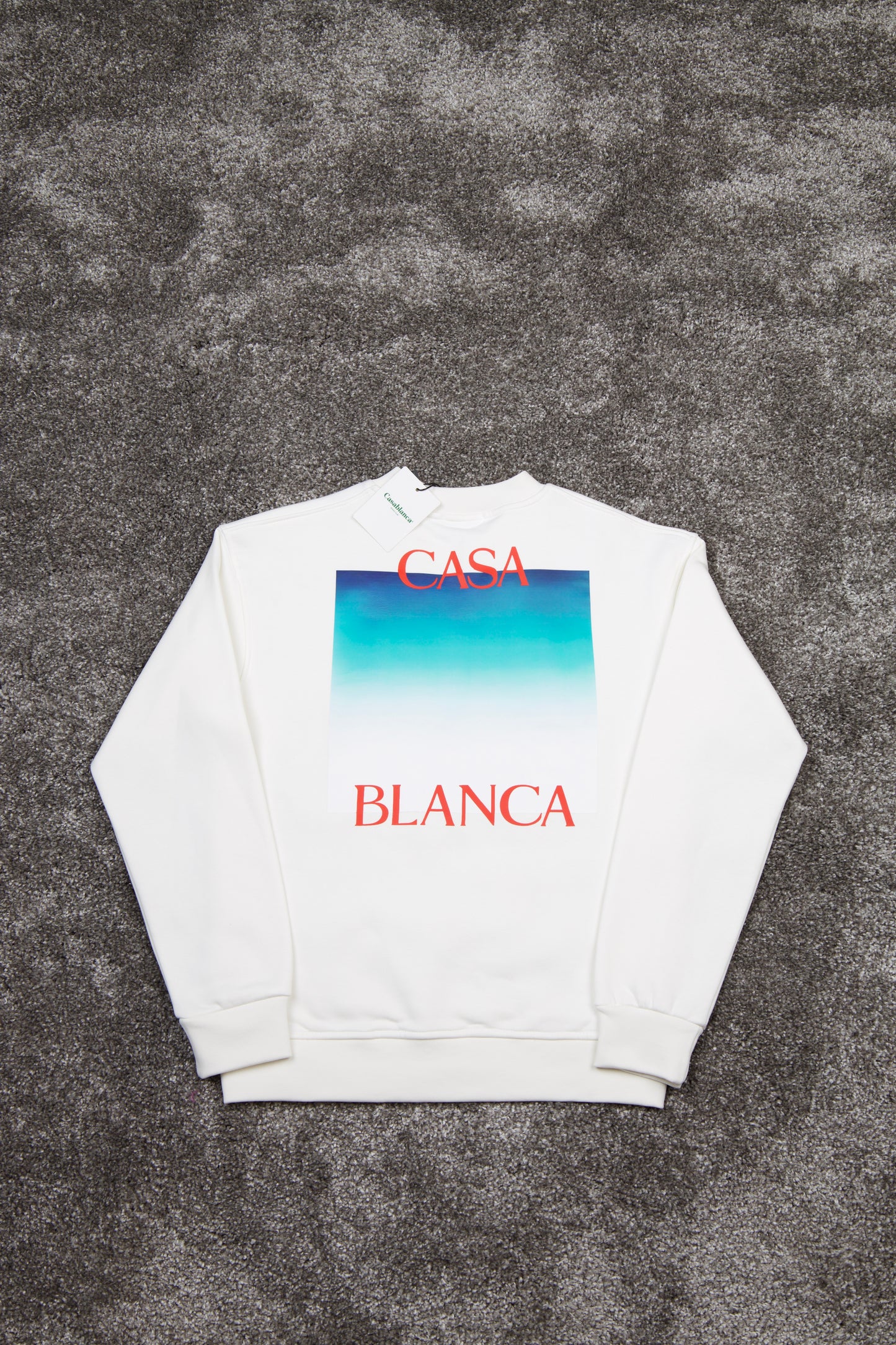 White sweatshirt with 'Casa Blanca' text and gradient design on a textured gray background